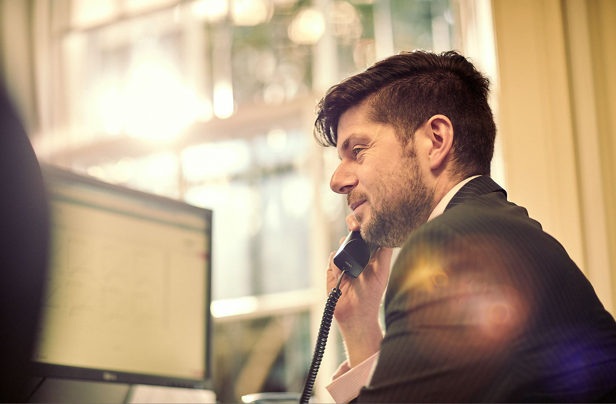 Man speaking on telephone and looking at computer