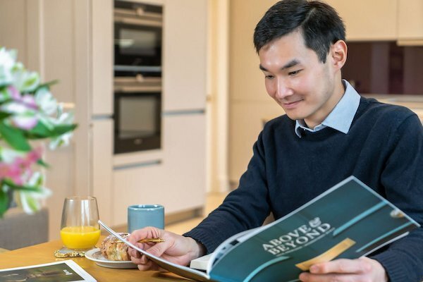 Young man sitting at table reading brochure