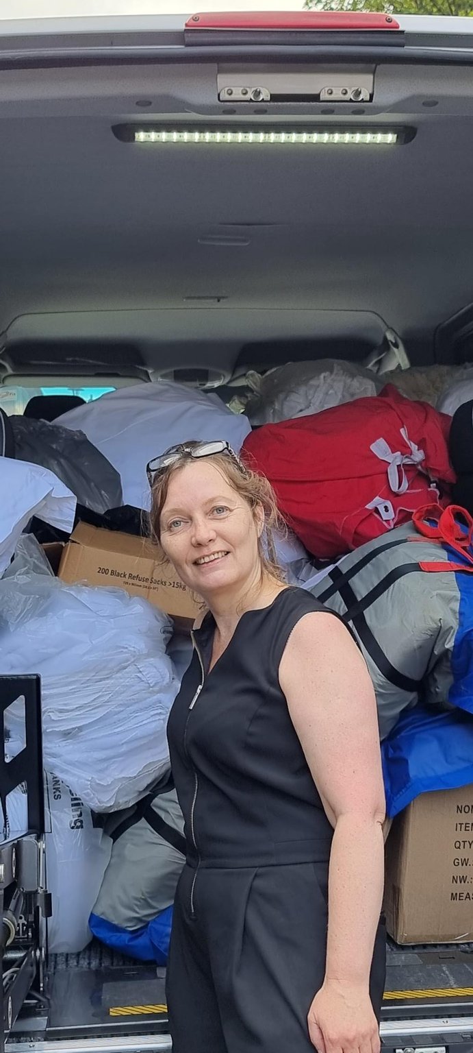 Lady standing at van filled with donation of linen
