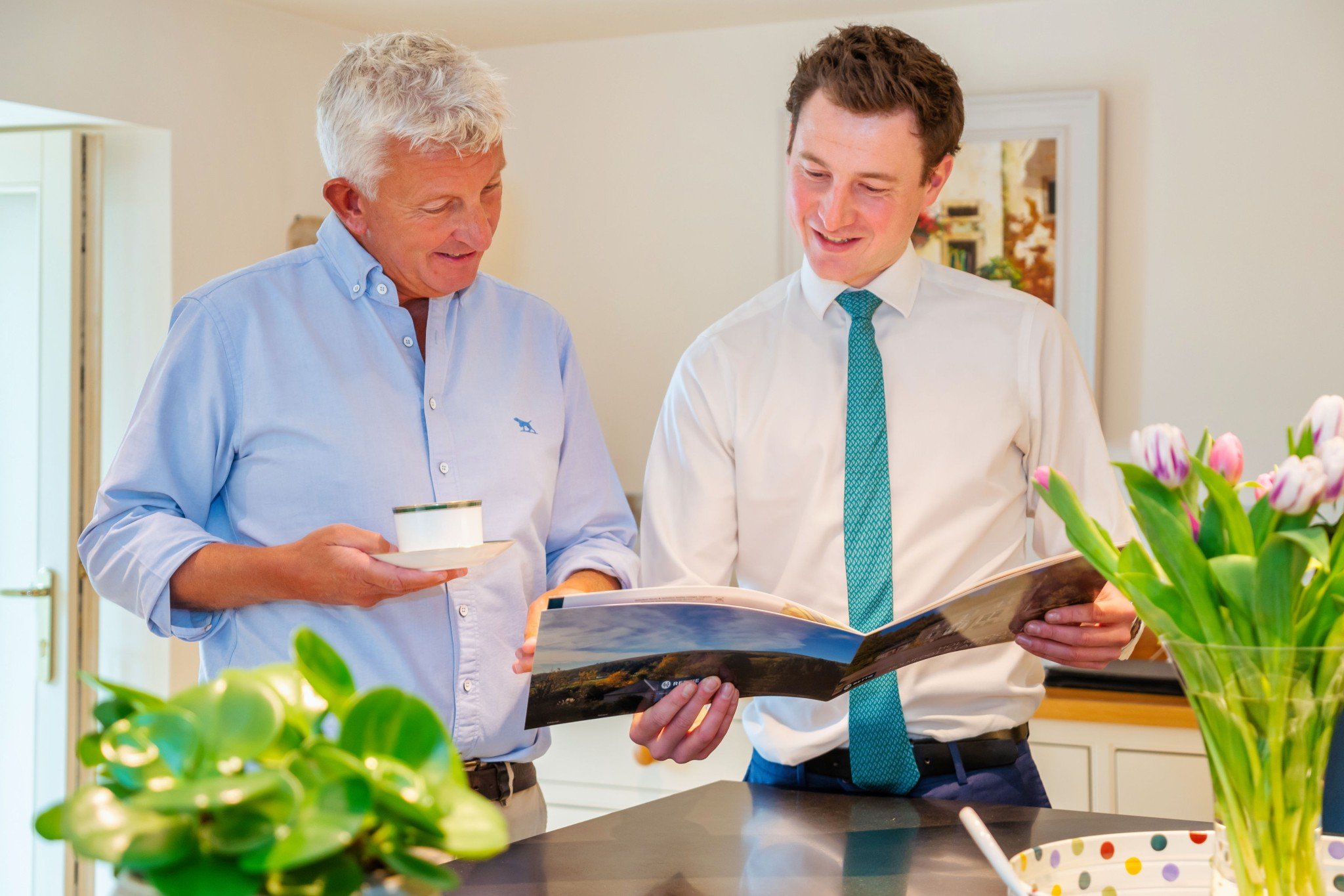 Two man standing in kitchen looking at a magazine