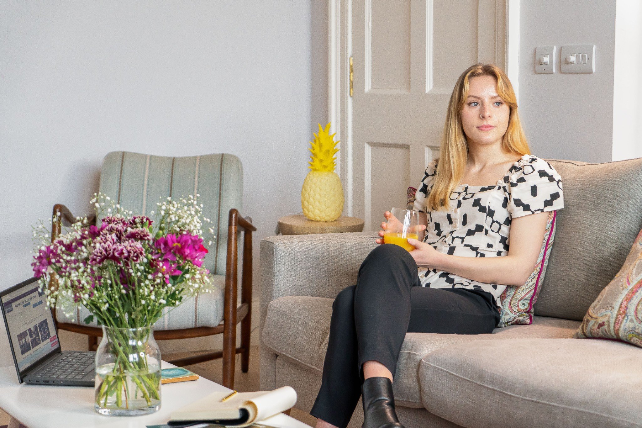 Lady with glass or orange juice sitting on sofa