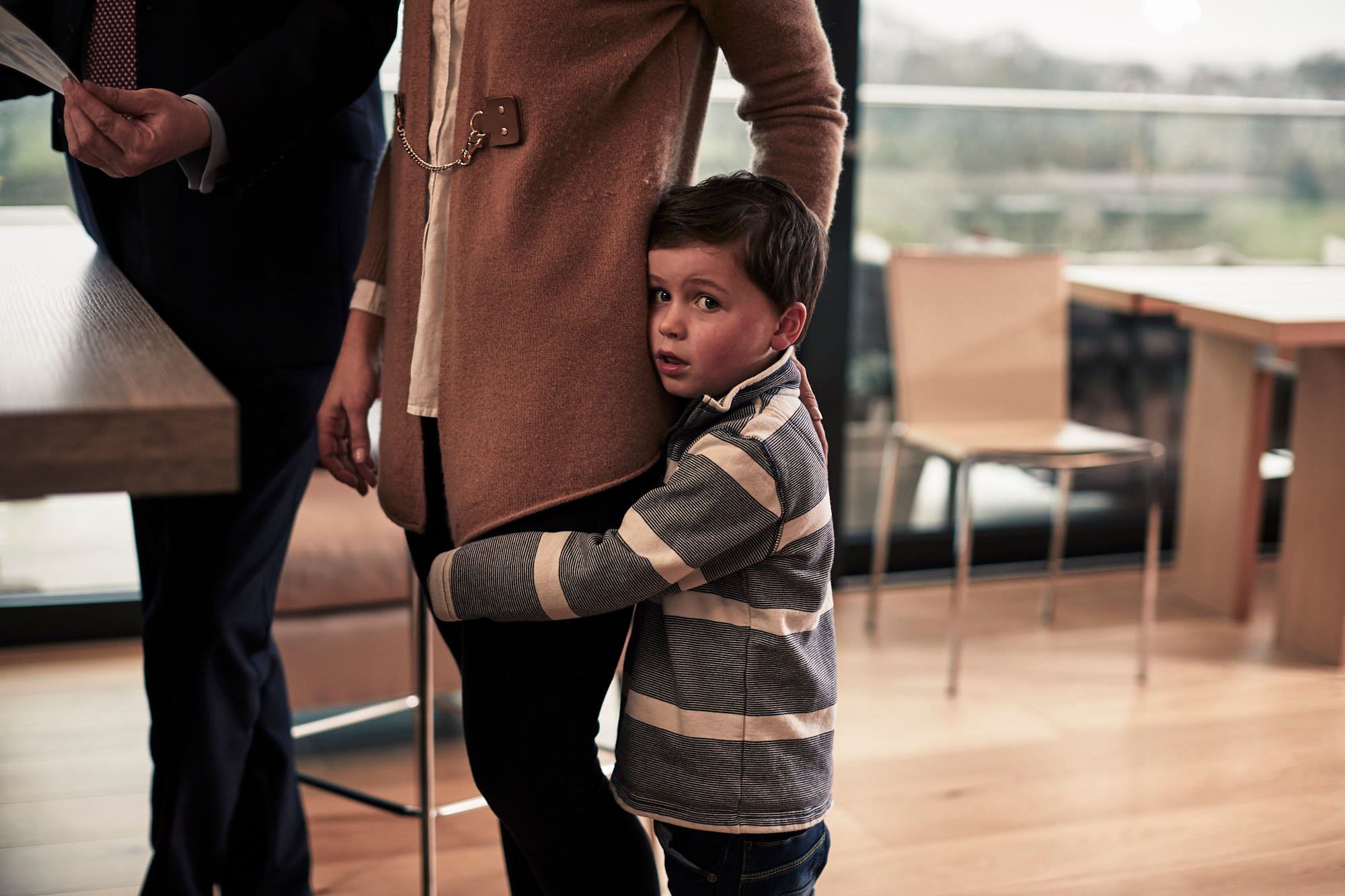 Young boy hugging his Mum's leg