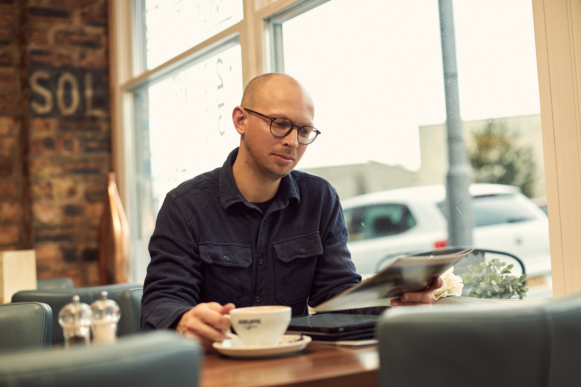 Young man sitting at table reading brochure