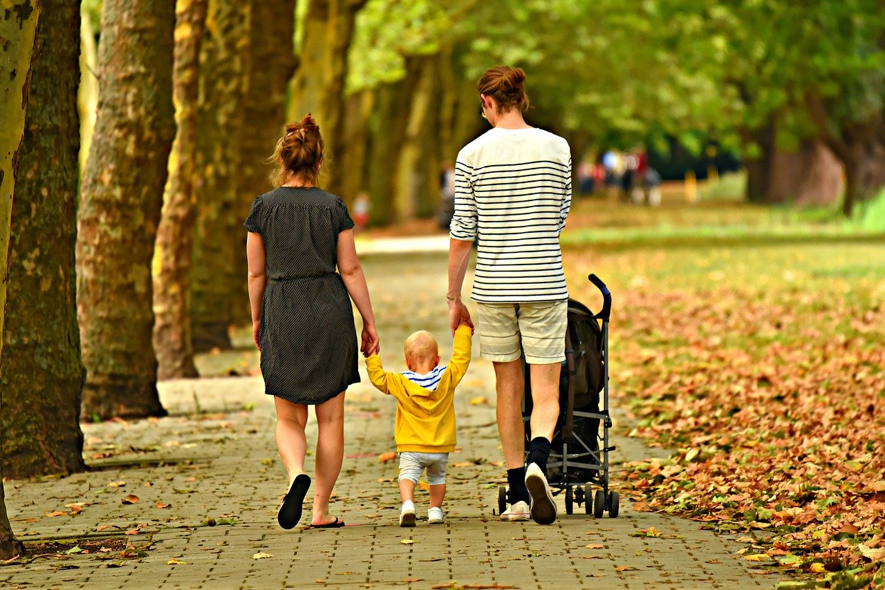Couple with toddler walking through a park
