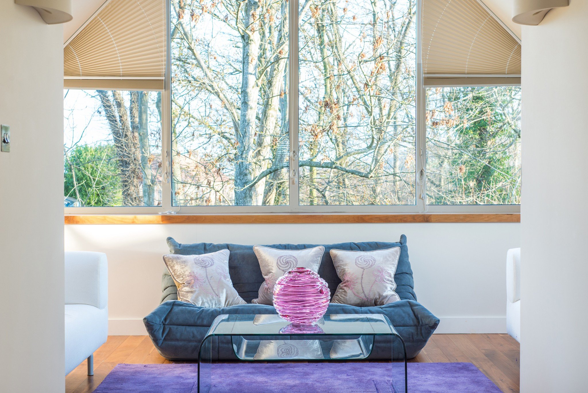 Blue sofa with cream cushions sitting under apex window