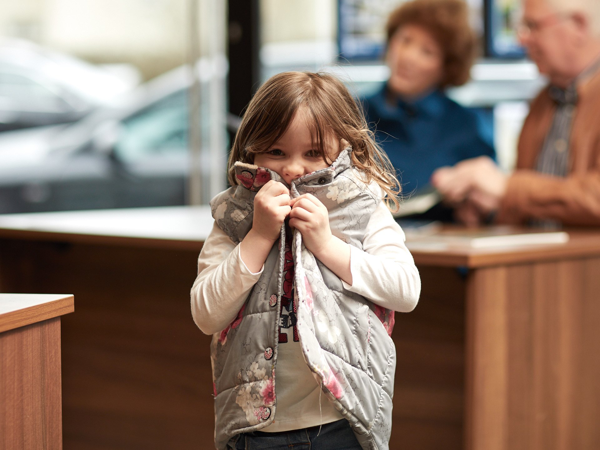 Small girl hiding behind her jacket and laughing